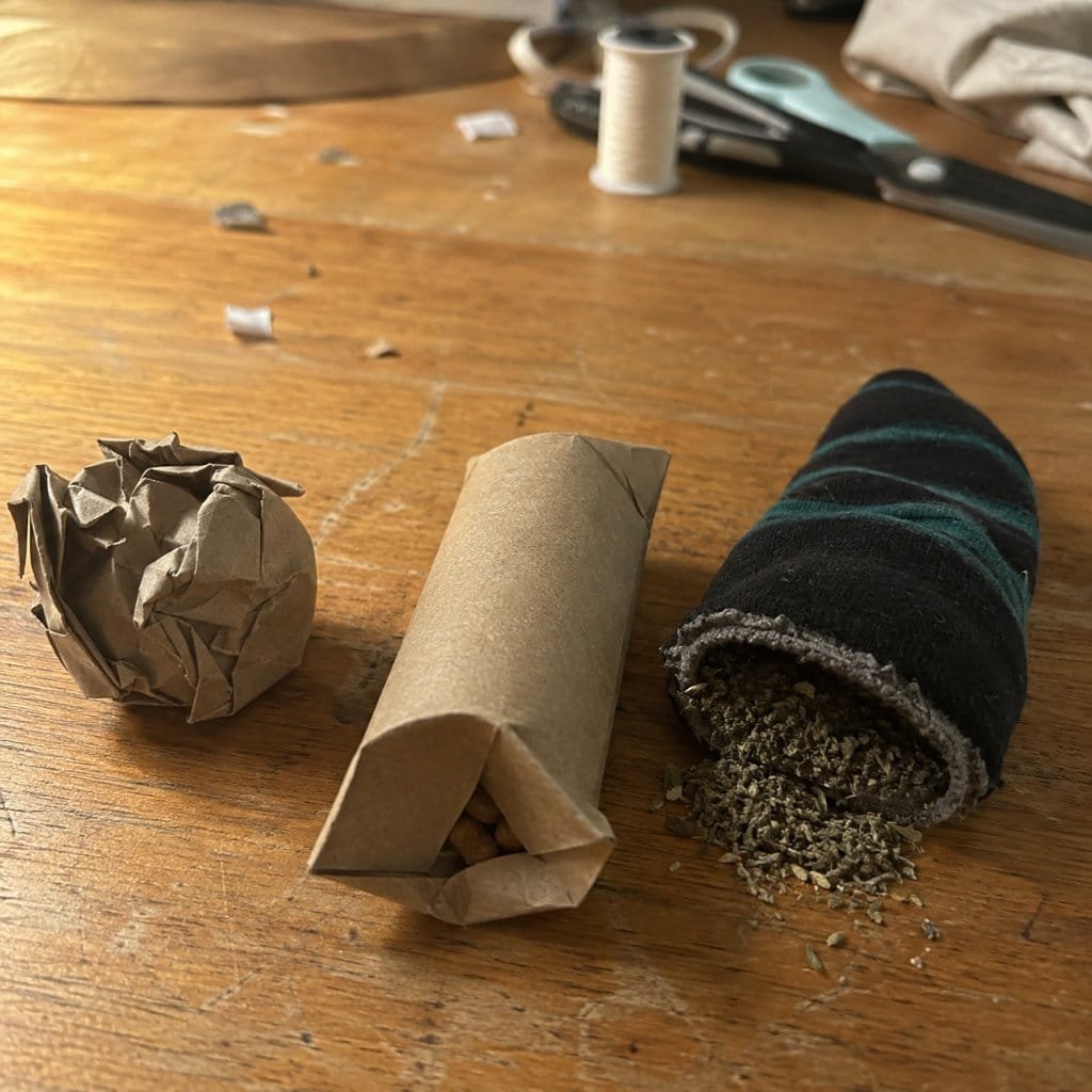 Homemade cat toys in progress on a kitchen table with catnip and a sock